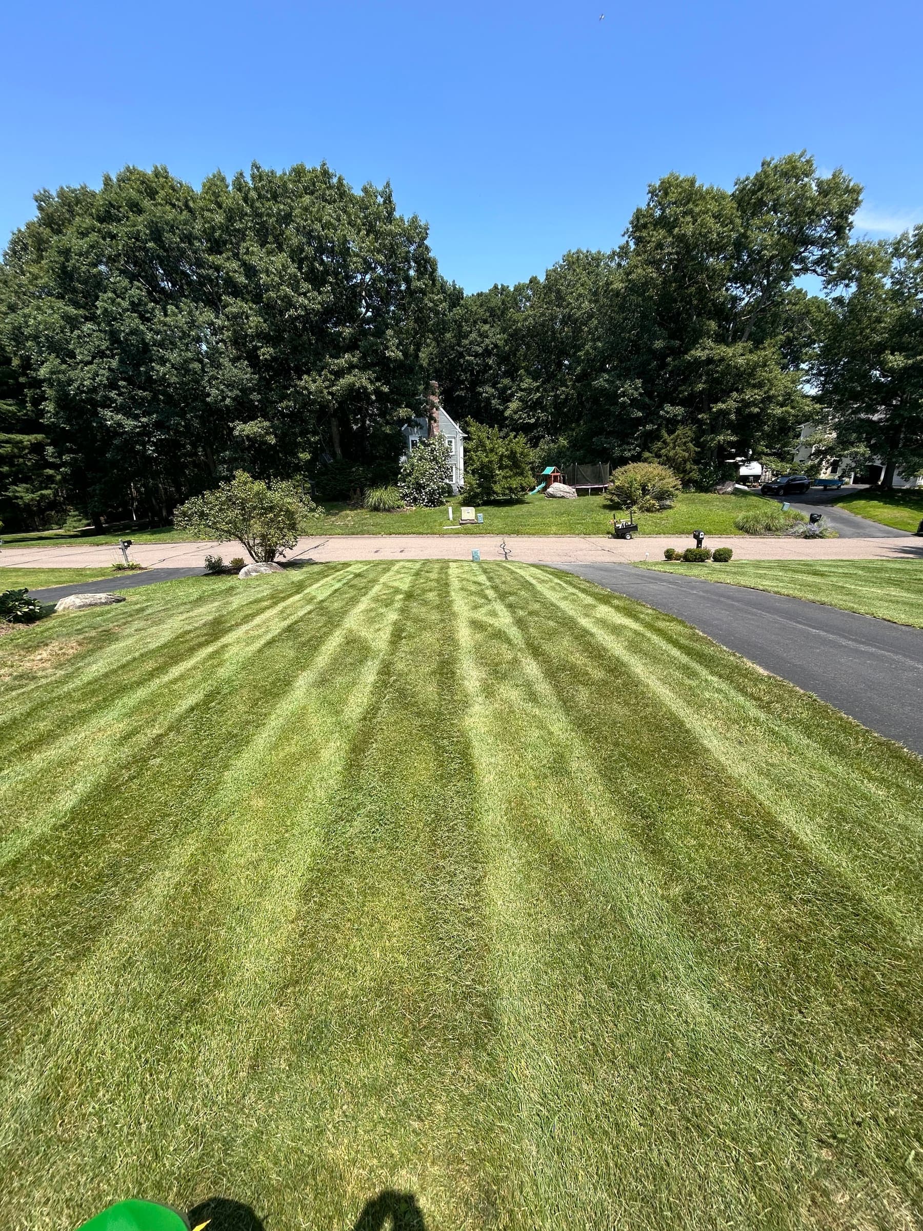 Wide roadside lawn in Madison, CT with fresh mower lines fanning out toward the street