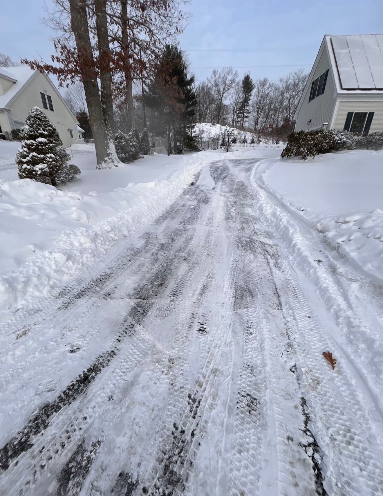 Residential driveway plowed down to the pavement between snowbanks after a winter storm in Madison, CT